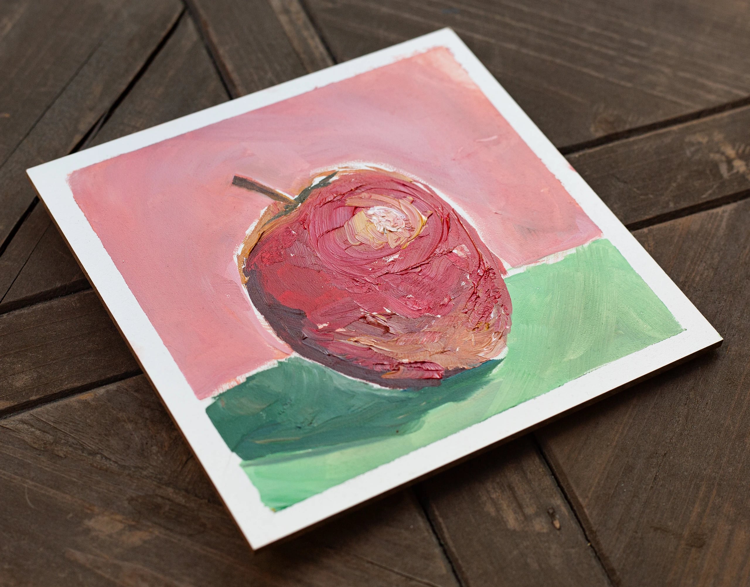 The Apple painting photographed at an angle on a dark wooden table.