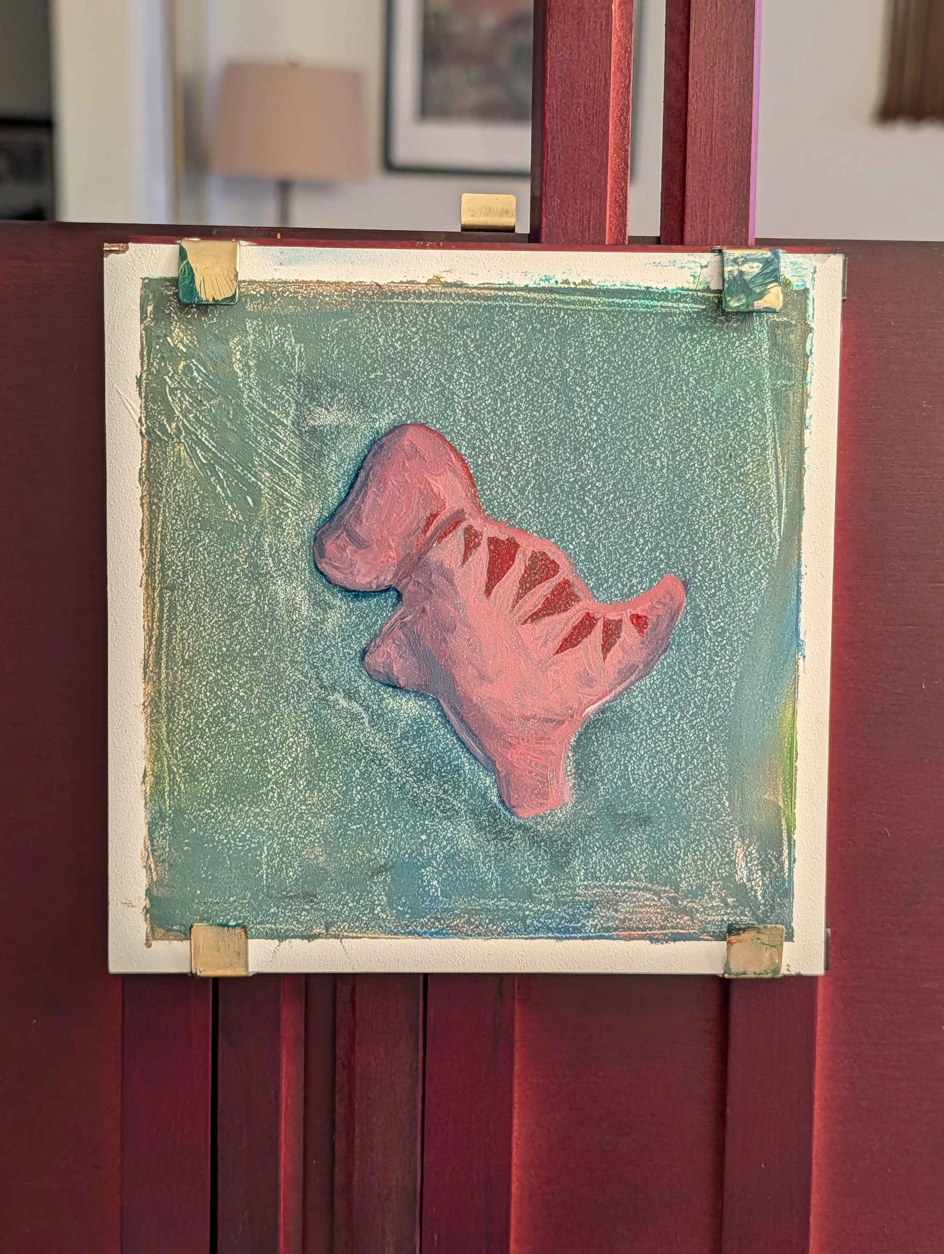 Work in progress: the dinosaur painting clipped to an easel, background scumbled in teal.